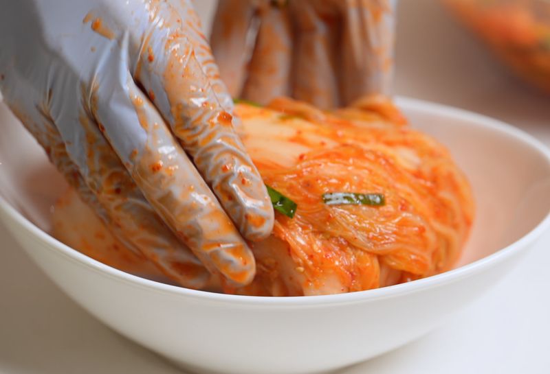 니트릴 장갑을 끼고 김치를 버무리는 모습